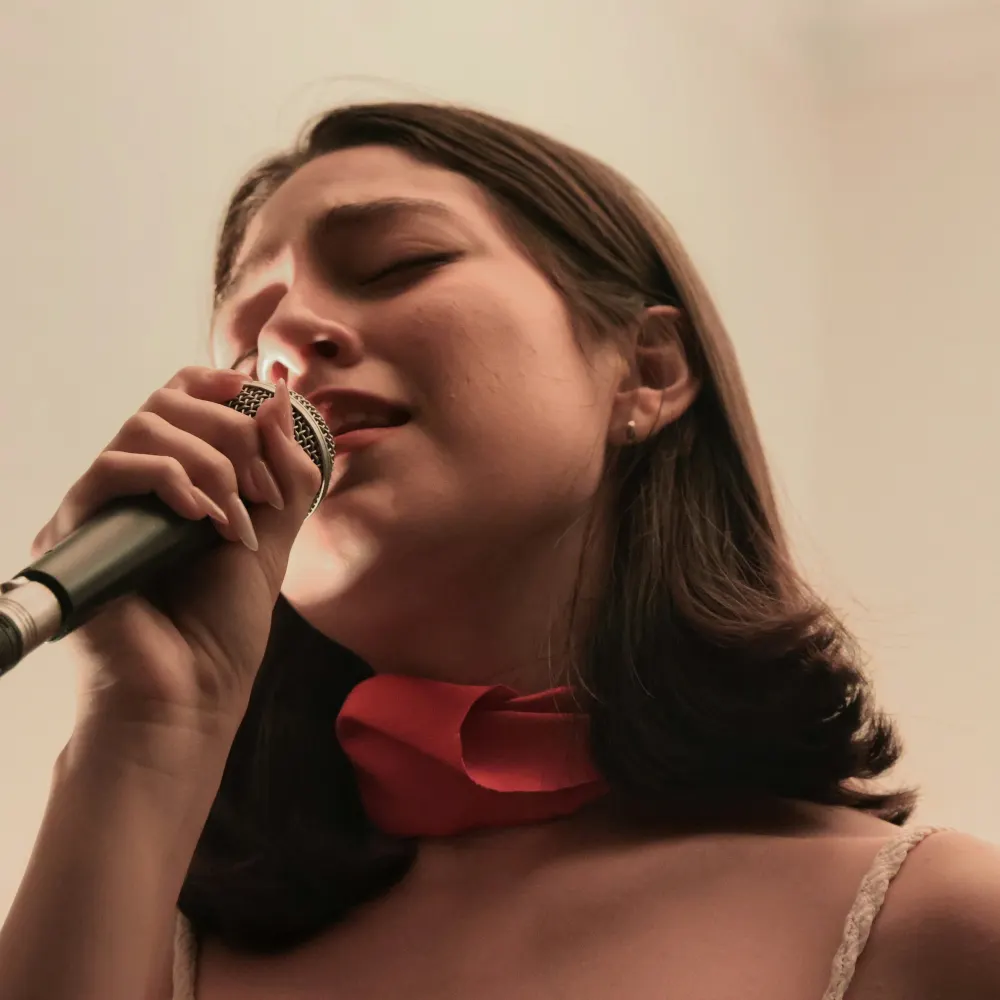 A woman singing into a microphone with her eyes closed